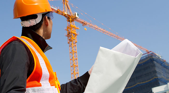 Construction worker looks at crane, if he experiences an accident he would need to contact a Miami crane accident lawyer